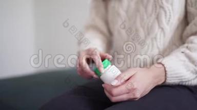 一个女人打开一罐药，把一粒药丸倒进她的手掌，并服用抗生素。 感冒，流感季节。 不健康